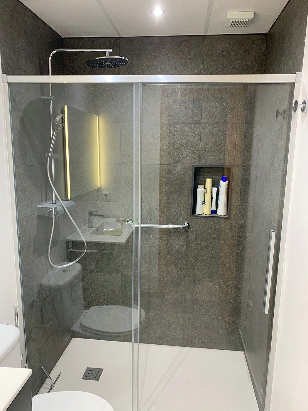 Ducha de obra con gres de gran formato y hornacina en un baño reformado en Sevilla