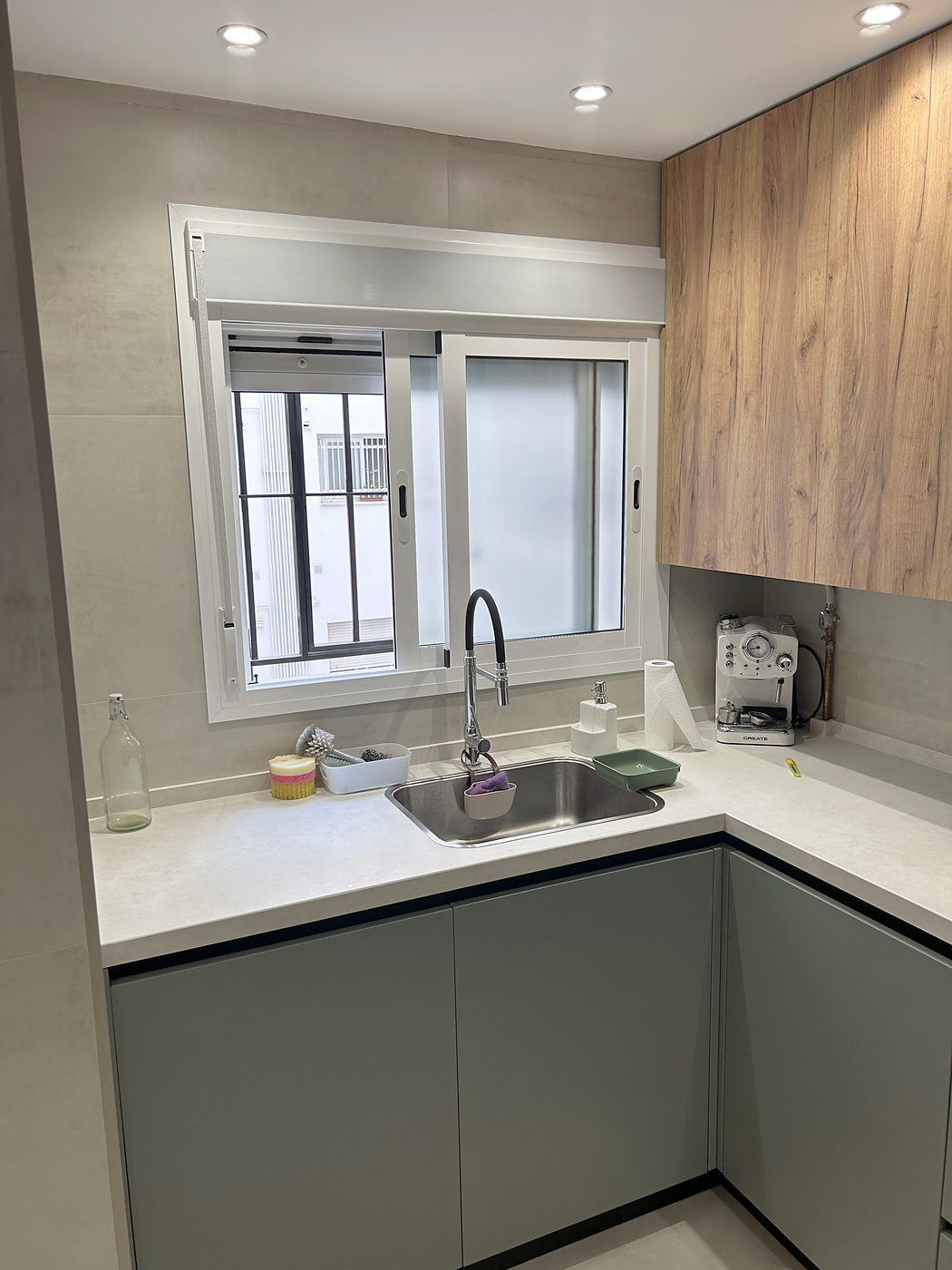 Cocina reformada en Sevilla en L, frentes verdes y roble con encimera clara