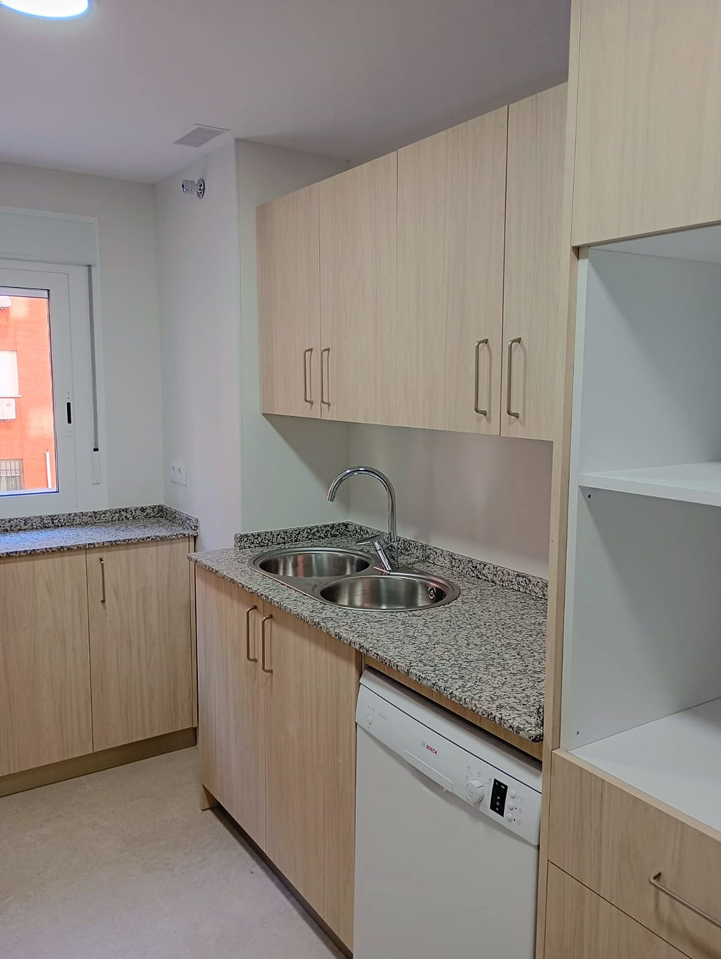 Zona de fregadero con lavavajillas y estantería abierta