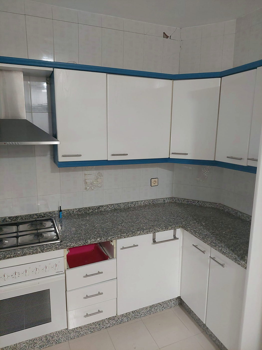 Antes de la reforma: cocina original con muebles blancos y cenefa